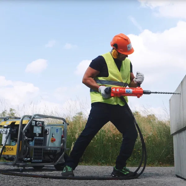 Doa-Super-Raptor-E-Aggregat-Bormaskin-1080px-1 Nærbilde av en arbeider som borrer i en betongblokk med hjelp av hydraulisk drill og aggregatet super raptor E