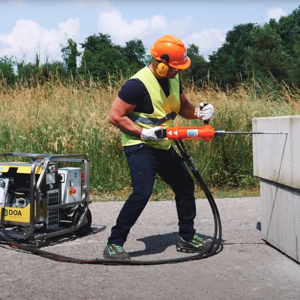 Doa-Super-Raptor-E-Aggregat-Bormaskin-1080px-2 Nærbilde av en arbeider som borrer i en betongblokk med hjelp av hydraulisk drill og aggregatet super raptor E